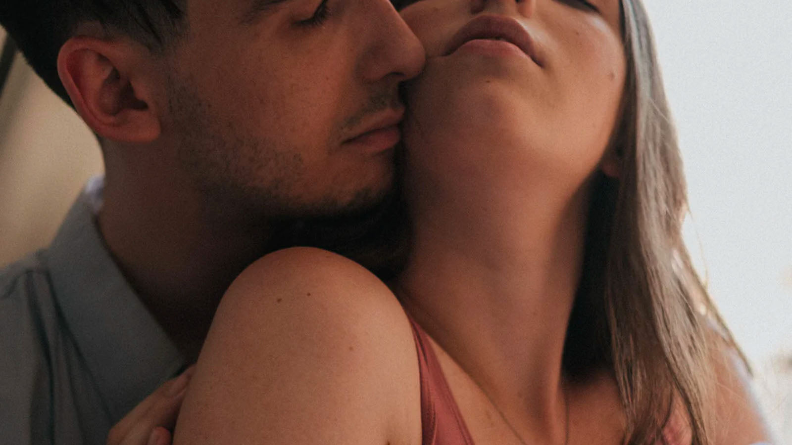 A close photograph of a couple embracing, his face resting against her cheek.