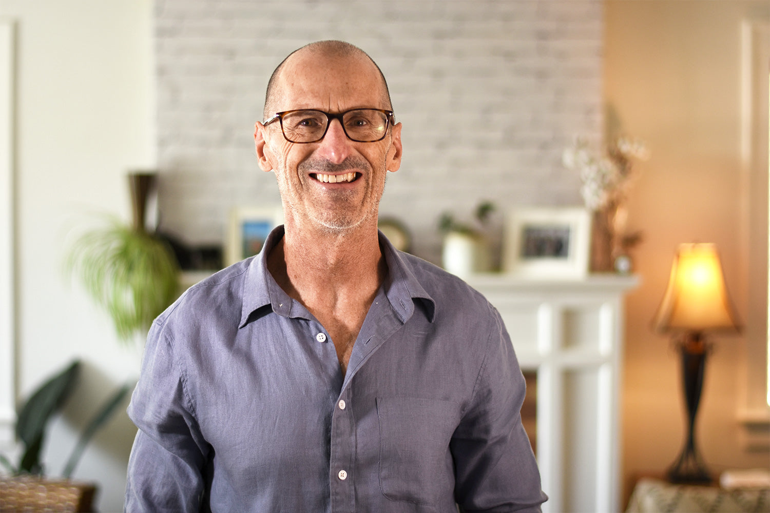 Nigel Shaw, founder of Xialla, smiling in a living room, wearing glasses and a linen shirt.