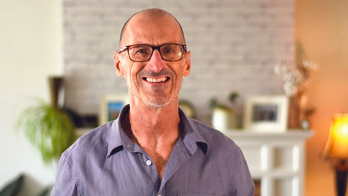 Nigel Shaw, founder and inventor of Xialla, smiling in a living room wearing glasses and a linen shirt.